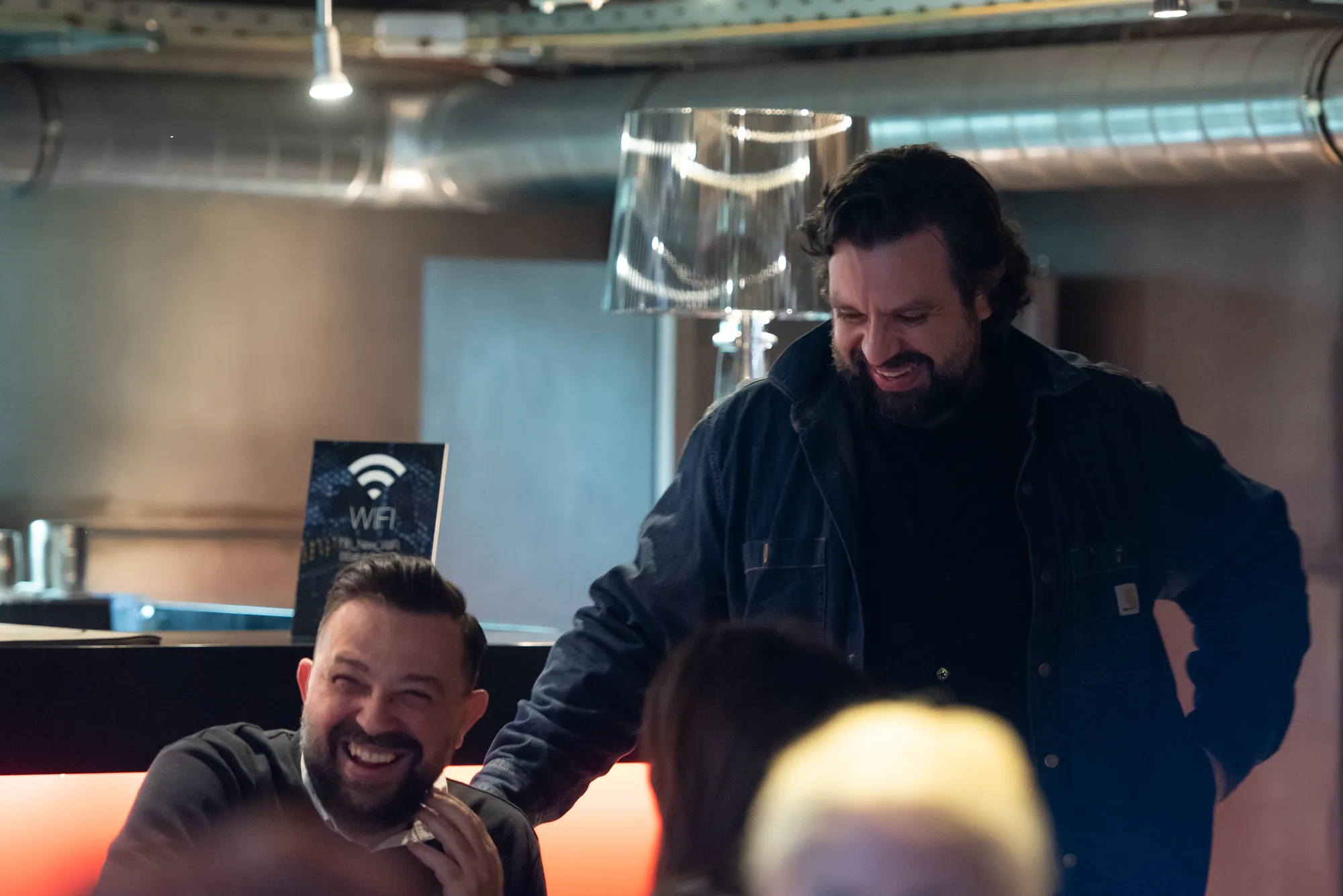 Two attendees laughing together at the bar during a break